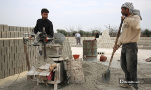عاملان سوريان يعملون على بناء وحدات سكنية أسمنتية عوضًا عن الخيام للنازحين في مخيمات في الشمال السوري- 15 من نيسان 2020 (عنب بلدي)
