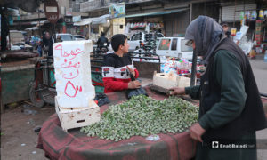 رجل يشتري لوز أخضر من طفل يبيعه على عربته في سوق مدينة إدلب- 7 من نيسان (عنب بلدي)