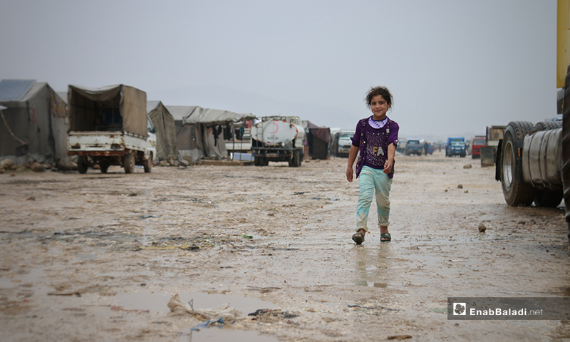 طفلة تسير وسط مخيم حلب لبيه في الأجواء الماطرة باليوم الأول من رمضان- 24 من نيسان (عنب بلدي)