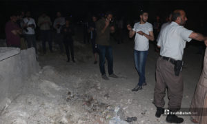 عناصر من الشرطة تبعد مدنينن عن مكان انفجار عبوة ناسفة لمعاينته - 14 أيار 2020 (عنب بلدي/ عاصم ملحم)