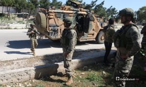 عناصر من الجيش التركي بجوار عربة عسكرية ينتشرون على الطريق الدولي حلب اللاذقية خلال تسيير الدورية المشتركة الحادية عشر - 14 أيار 2020 (عنب بلدي/ يوسف غريبي)