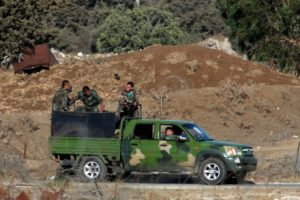 رجال يرتدون الزي العسكري يركبون شاحنة صغيرة في القنيطرة، على الجانب السوري من خط وقف إطلاق النار بين إسرائيل وسوريا، كما يُرى من مرتفعات الجولان التي تحتلها إسرائيل- 26 من تموز 2018 (رويترز).