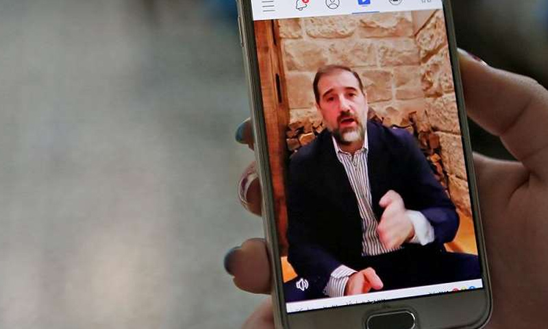 سيدة تشاهد مقطع فيديو على فيس بوك نشره رجل الأعمال السوري رامي مخلوف (AFP)