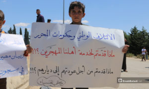 طفل يرفع لافتة في مظاهرة طوفان العودة ثاني أيام عيد الفطر على الطريق الواصل بين إدلب وسرمين - 25 أيار 2020 (عنب بلدي/ أنس الخولي)