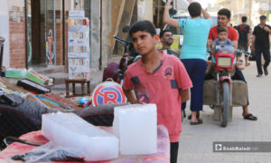 طفل بجوار بسطة لبيع ألواح البوظ، إذ زاد الطلب عليها بعد ارتفاع درجات الحرارة - 20 أيار 2020 (عنب بلدي/ عبد السلام مجعان)