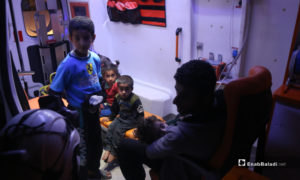 طفل في حضن والده أثناء التوجه إلى قسم الإسعاف مصاب  بتسمم في سيارة إسعاف نتيجة تناول طعام فاسد مقدم من أحد الجمعيات الخيرية في مخيم رعاية الطفولة شمال إدلب - 11 أيار 2020 (عنب بلدي)