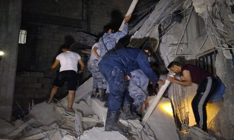 أشخاص يحاولون إخراج من هم تحت أنقاض البناء الذي سقط في حي الغراف باللاذقية- 23 من حزيران (سانا)
