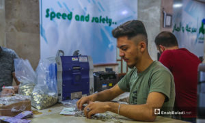 موظف داخل بنك الشام في مدينة إدلب يعمل على تصريف العملة السورية للتركية- 18 حزيران 2020 (عنب بلدي/ يوسف غريبي)