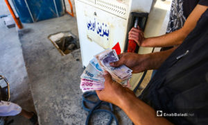 مواطن سوري يتداول العملة التركية في شراء المحروقات داخل مدينة إدلب شمال سوريا- 18 حزيران 2020 (عنب بلدي/ يوسف غريبي)