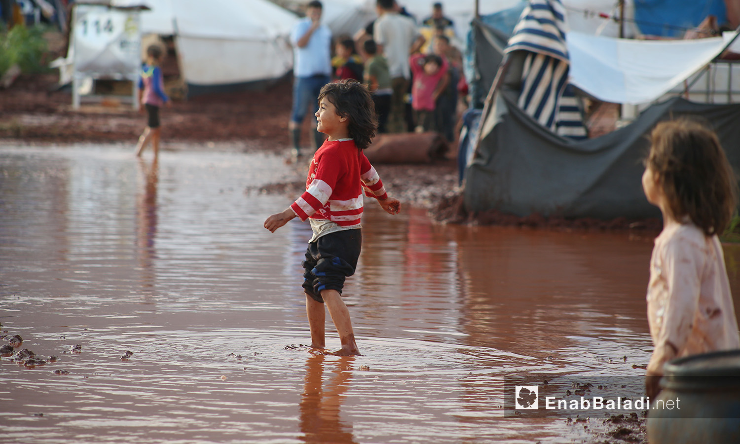 طفلة تغمر قدماها المياه بعد العاصفة المطرية التي ضربت مخيم "سهل الخير" في كفربني بريف إدلب الشمالي - 19 حزيران 2020 (عنب بلدي/يوسف غريبي)