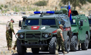 جنود روس بجانب عربات عسكرية روسية في سوريا (رويترز)
