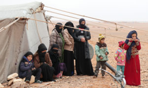لاجئون سوريون بجوار خيمة في مخيم الركبان على الحدود السورية الأردنية - 1 أيار 2019 (UNHCR)