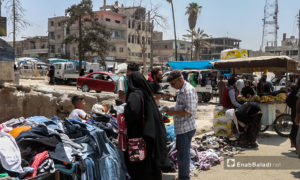 امرأة تشتري الثياب من أحد البسطات في أسواق مدينة الرقة - 30 تموز 2020 (عنب بلدي / عبد العزيز الصالح )