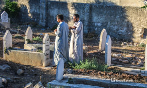 رجلان يزورا أحد قبور ذويهم في أول يوم عيد الأضحى ببلدة دابق في ريف حلب الشمالي - 31 تموز 2020 (عنب بلدي / عبد السلام مجعان )