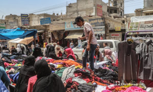 شاب يبع الألبسة عل أحدى بسطات سوق مدينة الرقة قبيل عيد الأضحى - 30 تموز 2020 (عنب بلدي / عبد العزيز الصالح )