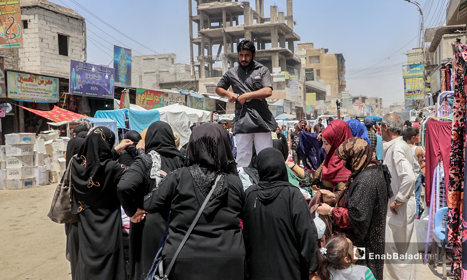 شاب يبيع الألبسة على بسطة في سوق مدينة الرقة قبيل عيد الأضحى - 30 تموز 2020 (عنب بلدي / عبد العزيز الصالح )