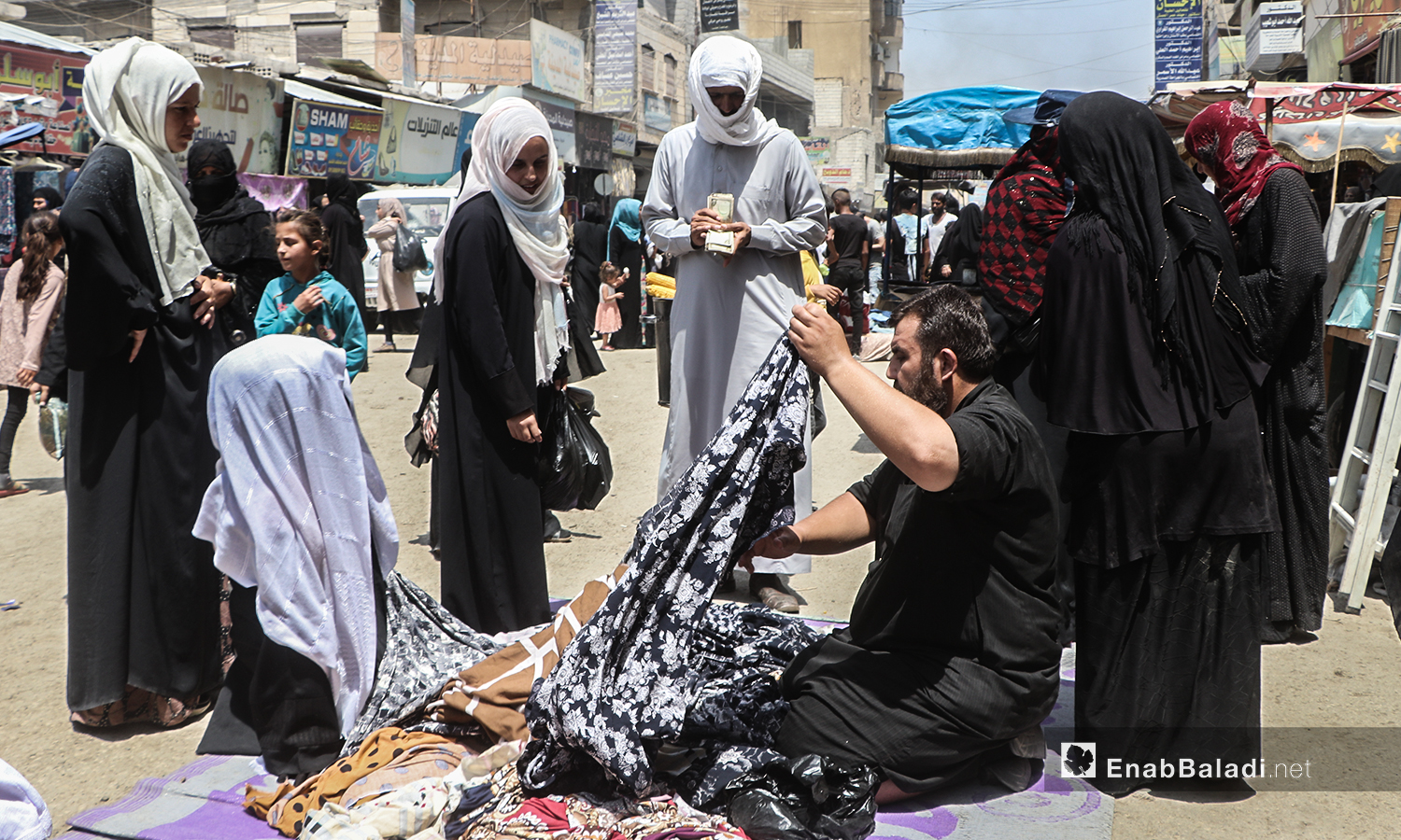 شاب يبيع الألبسة على بسطة في سوق مدينة الرقة قبيل عيد الأضحى - 30 تموز 2020 (عنب بلدي / عبد العزيز الصالح )