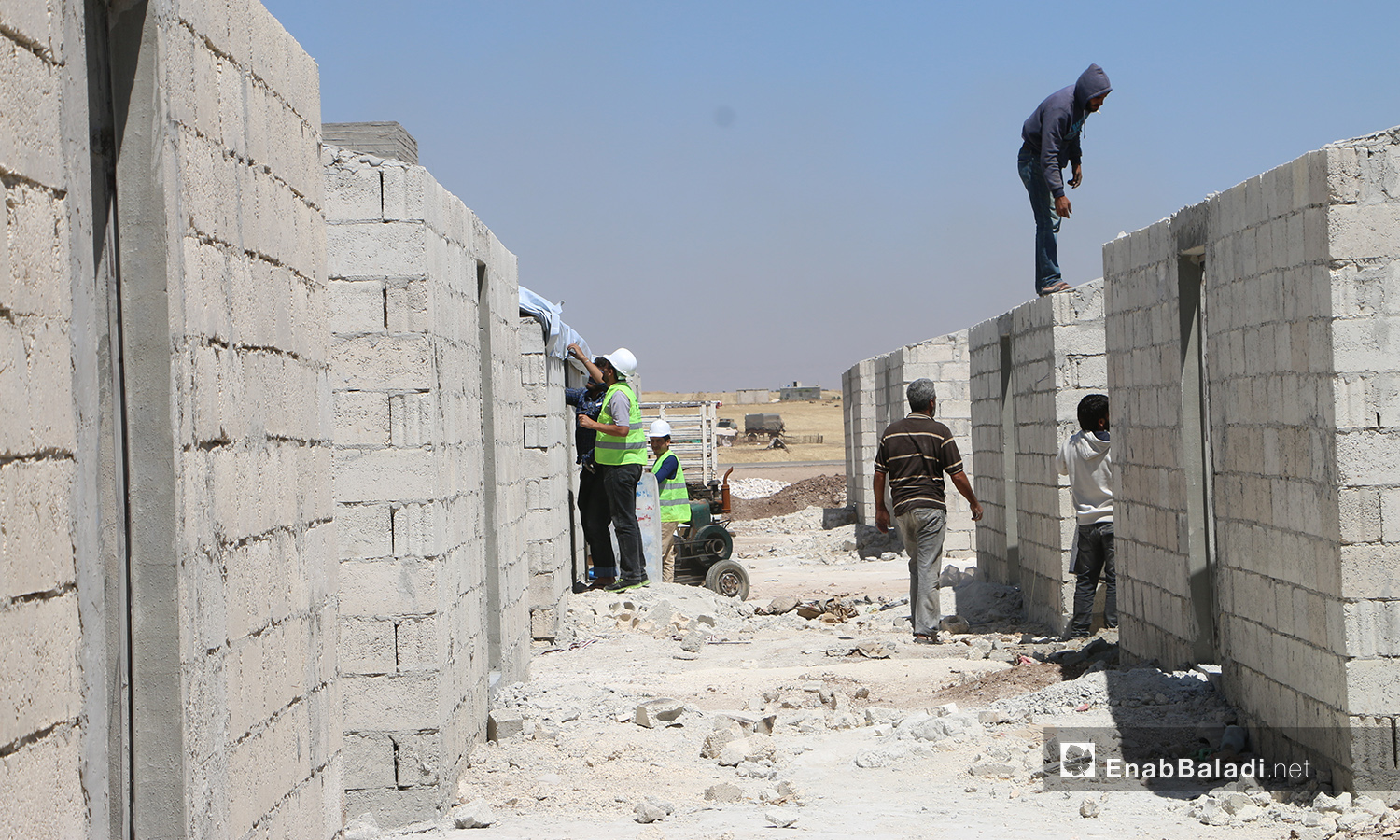 عمال بناء ضمن مشروع الكتل السكنية عوضًا عن الخيام في قرية بحورته بريف حلب الشمالي - 26 حزيران 2020 (عنب بلدي/عبد السلام مجعان)
