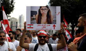 رجل لبناني يحمل صورة الممثلة اللبنانية ميا خليفة في أثناء مشاركتها في تجمع حاشد في وسط بيروت - 20 تشرين الأول 2019 (AFP)

