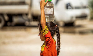 طفلة سورية نازحة تحمل المياه إلى مخيمها في مدينة الحسكة شمالي سوريا - 24 من آب 2020 (فرانس برس)
