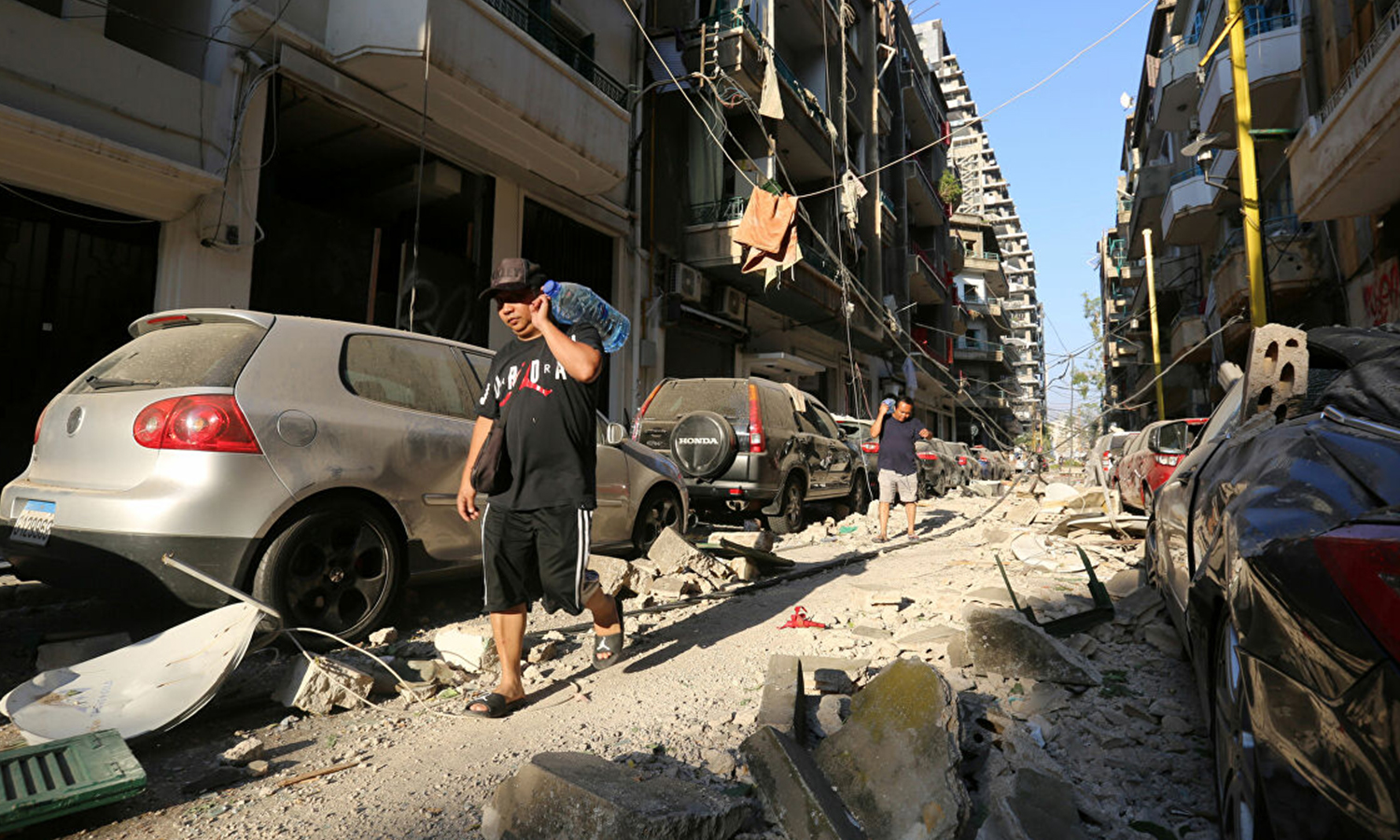رجل يحمل ماء عقب انفجار بيروت (رويترز)