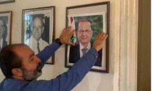 شخص يعيد تعليق صورة الرئيس اللبناني ميشيل عون في مبنى وزارة الخارجية بعد أن أزالها محتجون 10 من آب 2020 (التيار الوطني الحر)