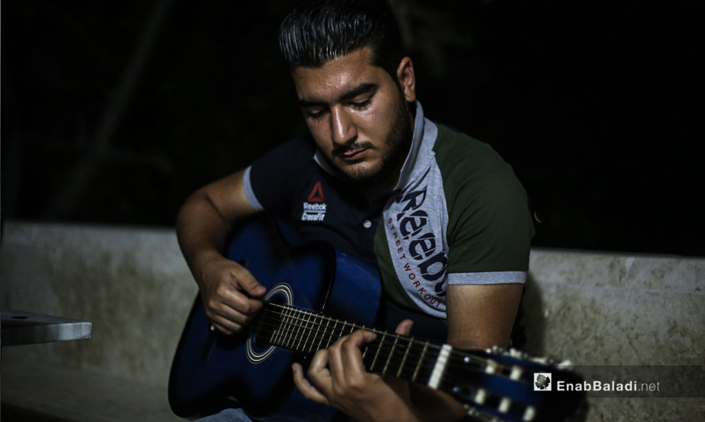 مازن الشيخ يعزف على الجيتار في منزله ببلدة عقربات شمال مدينة إدلب -08 أيلول 2020 (عنب بلدي/ يوسف غريبي)