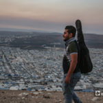 مازن الشيخ يحمل جيتاره على تله بلدة عقربات المطلة على المخيمات والقرى  -08 أيلول 2020 (عنب بلدي/ يوسف غريبي)

