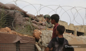 ينظر طفلان إلى النقطة العسكرية التركية التي تحيطها الأسلاك الشائكة في بلدة المسطومة جنوبي إدلب - 11 أيلول 2020 (عنب بلدي)