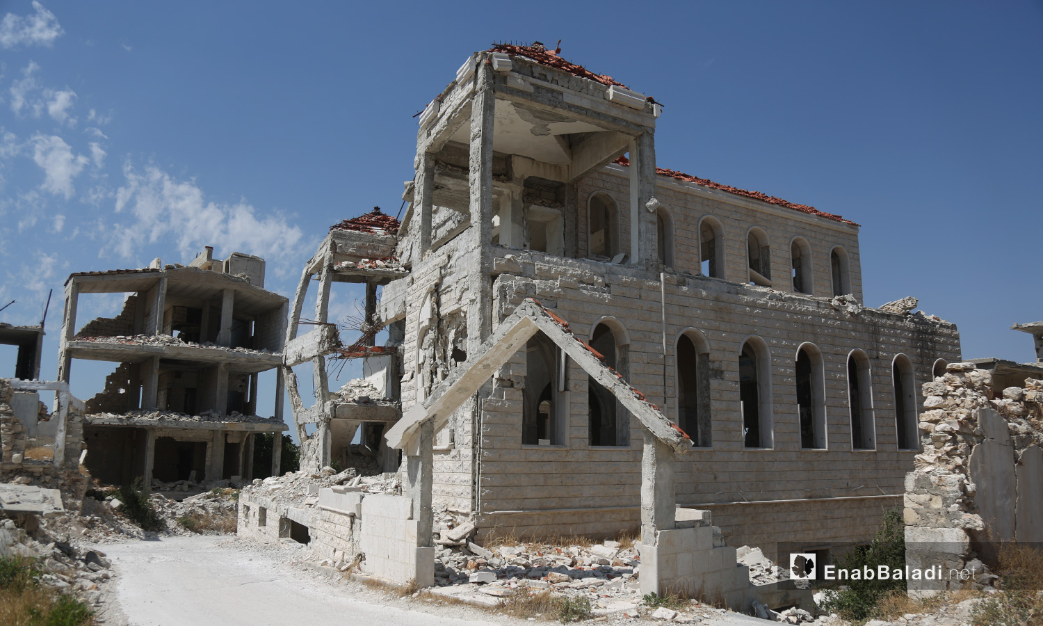 مدخل الكنيسة الإنجيلية في قرية الغسانية تعرض للقصف من قبل قوات النظام خلال سنوات الحرب - تموز 2020 (عنب بلدي)