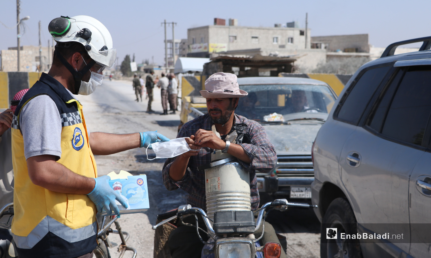 متطوع من الدفاع المدني يقدم كمامة لسائق دراجة نارية في مدينة الباب في ريف حلب الشمالي - 24 أيلول 2020 (عنب بلدي/ عاصم الملحم)