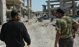 عنصر من الجيش الحر وحوله آثار الدمار الذي تعرض له حي طرق السد في درعا نتيجة قصف النظام - 23 كانون الثاني 2017 (الهيئة السورية للإعلام)
