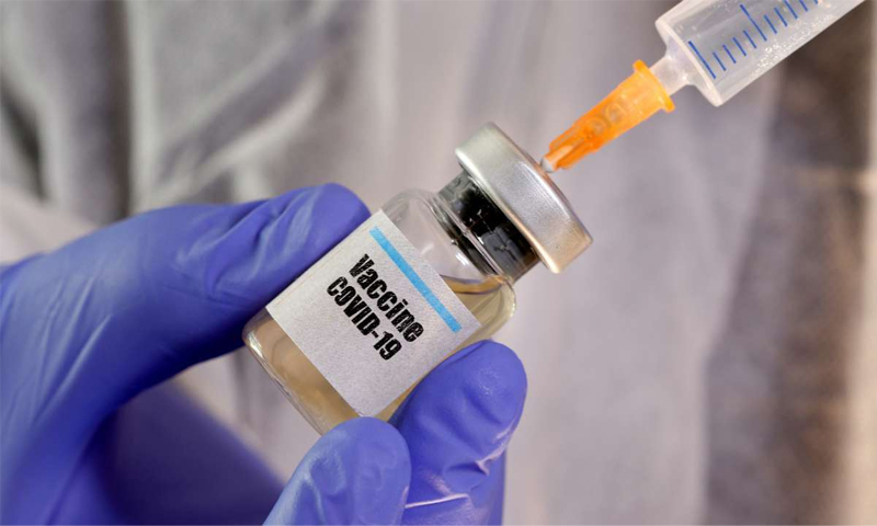 صورة تعبيرية لامرأة تحمل عبوة للقاح فيروس "كورونا" - نيسان 2020 (رويترز)