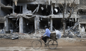 رجل يركب دراجة هوائية بالقرب من مبان متضررة في حي جوبر بالعاصفة دمشق- 27 من تشرين الأول 2015 (رويترز)
