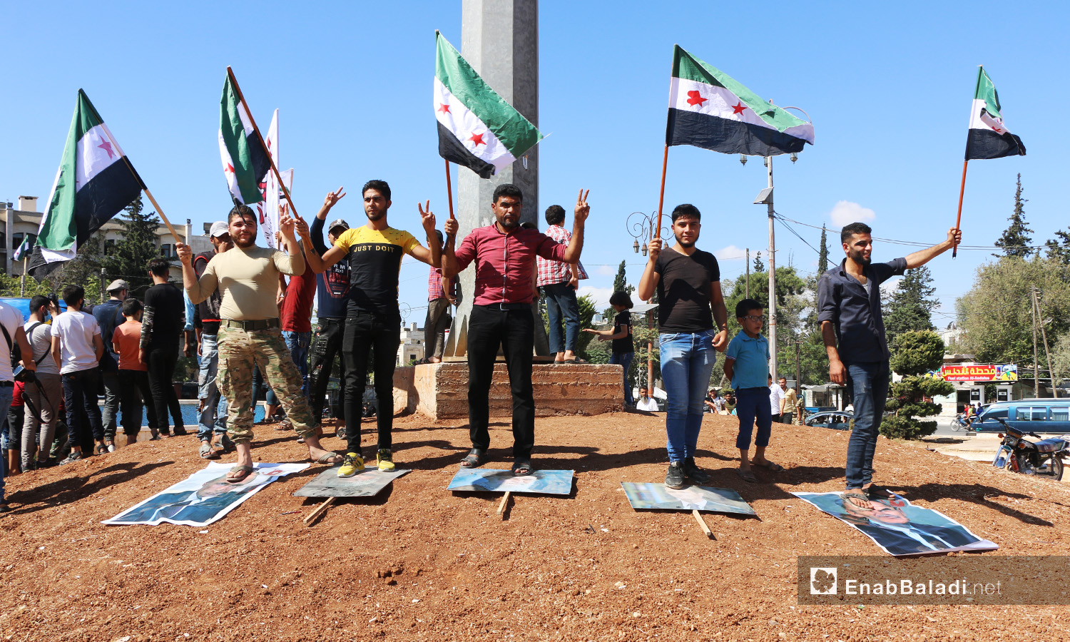 داس المتظاهرون على صور رئيس النظام السوري الأسد الأب والابن وحلفائهم قادة روسيا وإيران - 2 تشرين الأول 2020 (عنب بلدي/ أنس الخولي)