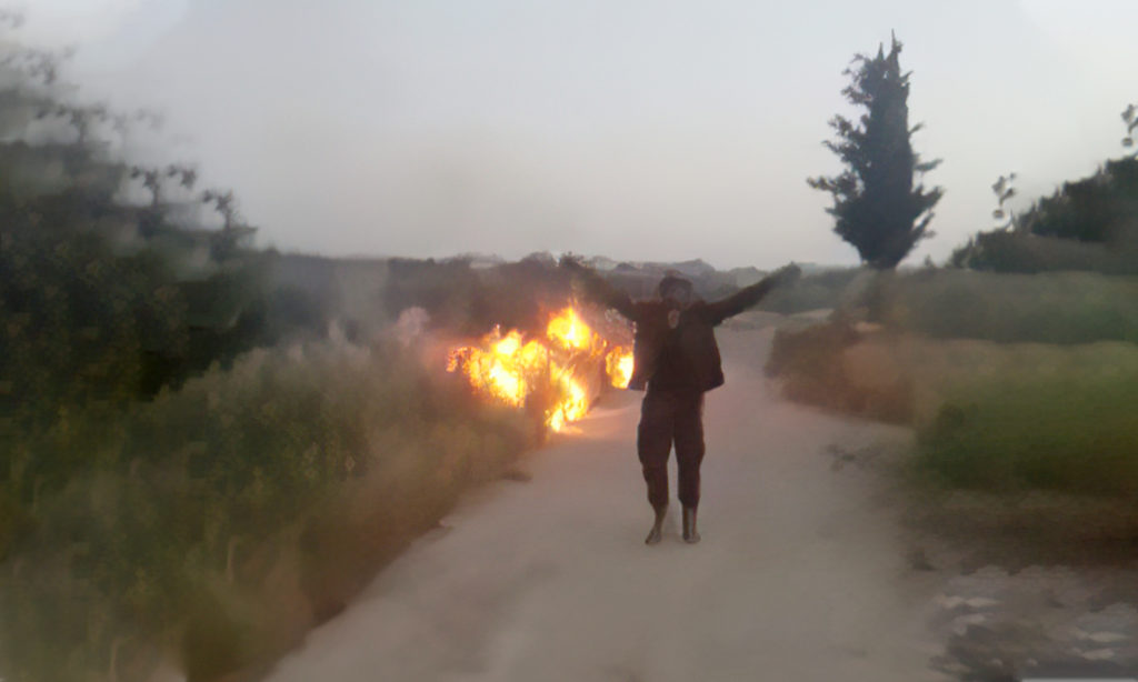 شخص بلباس عسكري يضرم النار في أرض زراعية (من تسجيل مصور متداول)