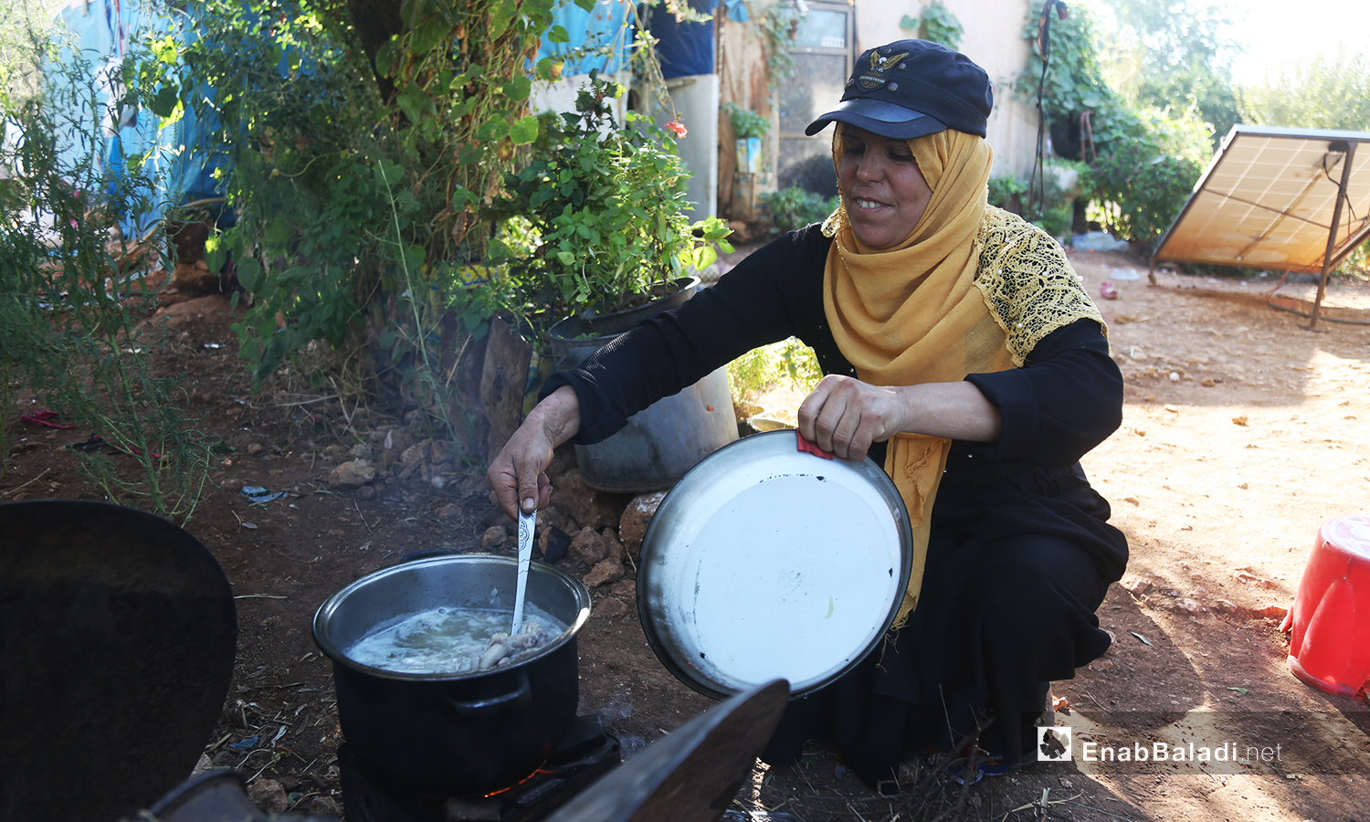 تطهو حورية طعام عائلتها بين النباتات المحيطة بخيمتها  - تشرين الأول 2020 (عنب بلدي/ يوسف غريبي)