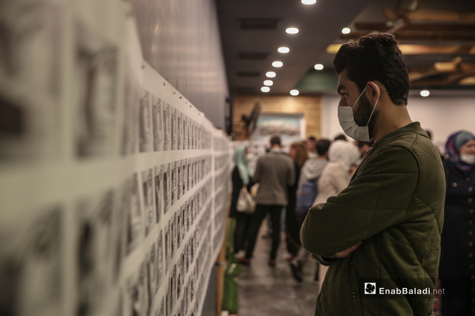 شاب ينظر إلى صور ضحايا أطفال سوريين في معرض "سُكّان الذاكرة" الذي يوثق بالصور و الاسماء و التواريخ 4600 طفل سوري على لوحة طولها 70 متر في اسطنبول - 13 تشرين أول (عنب بلدي/ عبد المعين حمص)
