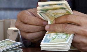 رجل يقوم بعد مبلغ مالي من العملة السورية (تعبيرية)