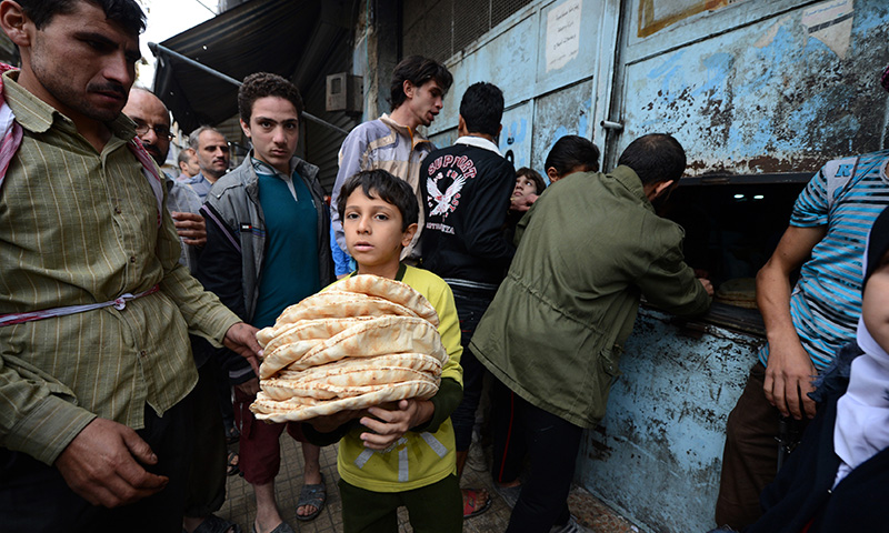 طفل سوري بعد حصوله على حصته من الخبز - المصدر (AFP)