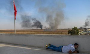 صحفي يختبئ في بلدة أكجاكال بالقرب من الحدود التركية- السورية في الوقت الذين سقطت فيها قذائف هاون قريبًا من المكان- 10 من تشرين الأول 2019 (فرانس برس/ بولينت كيليش)