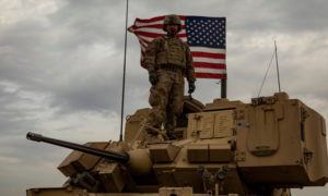 جندي من قوات التحالف يقف على عربة مدرعة وخلفه العلم الأمريكي – 24 من تشرين الثاني 2020 (التحالف الدولي)
