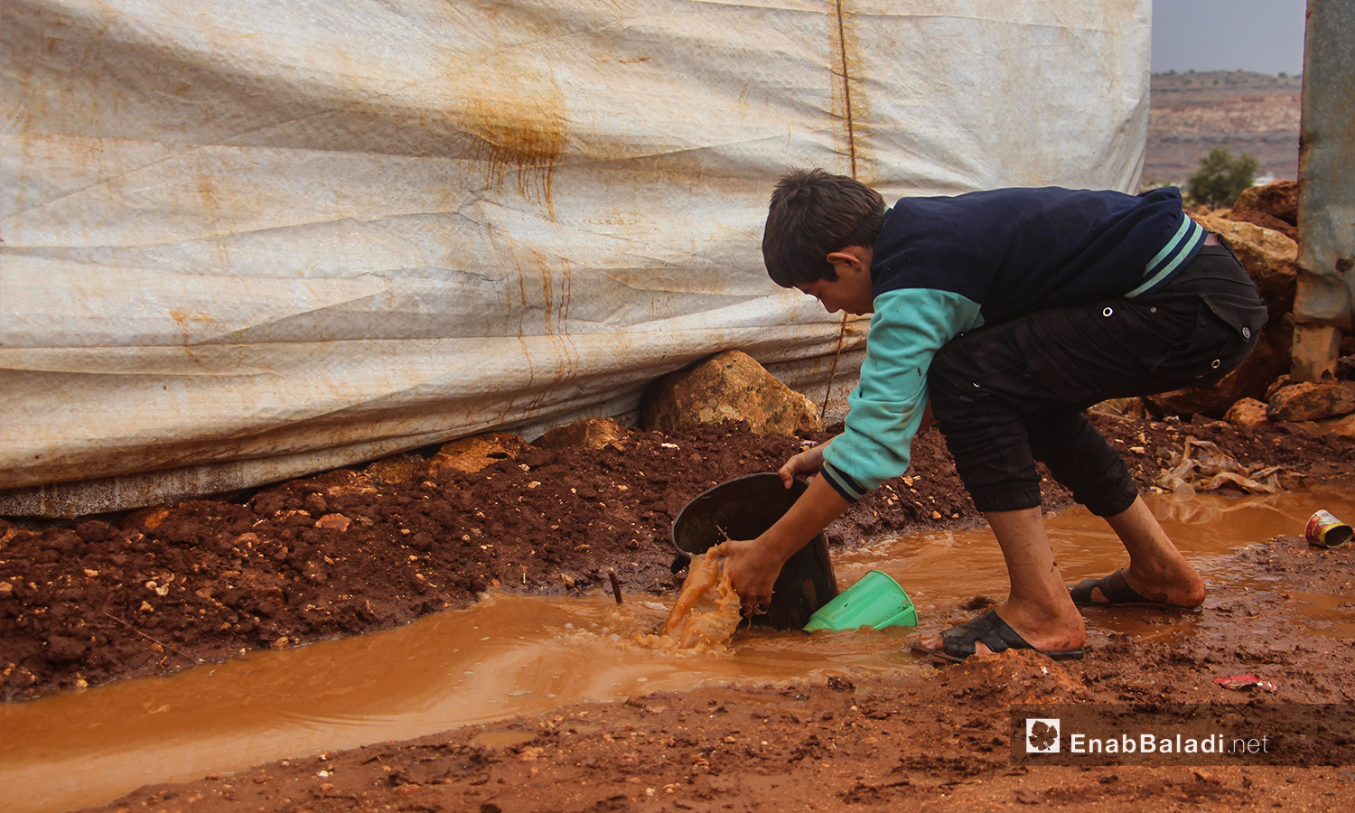 طفل يبعد المياه من بين الخيم بعد هطول الأمطار في مخيم الرمضون على أطراف قرية كفر عروق شمالي إدلب - 2 تشرين الثاني 2020 (عنب بلدي/إياد عبد الجواد)