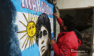 رسام الغرافيتي عزيز أسمر يرسم نجم كرة القدم الأرجنتيني الراحل دييغو مارادونا - 26 تشرين الثاني 2020 (عنب بلدي/ يوسف غريبي)