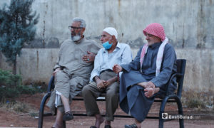 ثلاثة رجال يجلسون على مقعد في أحد شوارع مدينة الباب بريف حلب الشمالي دون الالتزام بالتباعد الاجتماعي في حين ينزل أحدهم الكمامة التي يرتديها إلى ذقنه - 24 تشرين الثاني 2020 (عنب بلدي/ عاصم الملحم)