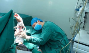 الجراح الصيني لو شانبينج نائما بجانب مريض بعد ساعات من العمل داخل غرفة العمليات في مشفى بمدين قوبيانغ الصينية 3 من كانون الأول 2019  (Guiyang Evening News)
