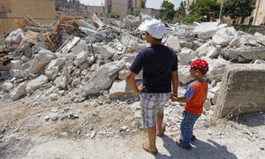 طفلان فلسطينيان يقفان على أطلال منزلهما في فلسطين، وكالة وفا)