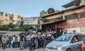 تحت لافتات حماية المستهلك طابور من المواطنين أمام باب الشركة العامة للمخابز في مدينة دمشق- 22 من تموز 2020 (عدسة شاب دمشقي)
