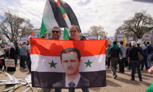  متظاهران يحملان العلم السوري عليه صورة بشار الأسد في مظاهرة مناهضة لإيباك في البيت الأبيض بواشنطن - 24 آذار 2019 (shutterstock)