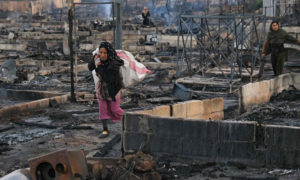 سوريون يعودون إلى مخيمهم بعد حرقه في شمالي لبنان 27 من كانون الأول 2020 (AFP)